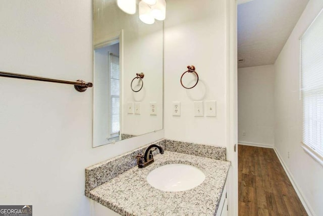 bathroom featuring baseboards, wood finished floors, and vanity