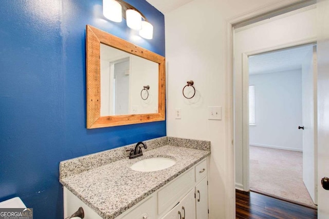 bathroom with wood finished floors, vanity, and baseboards