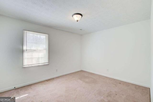 carpeted spare room with a textured ceiling and baseboards