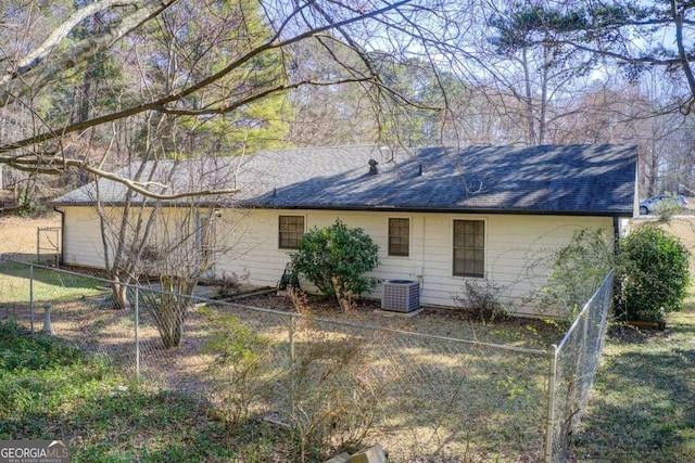 rear view of house featuring fence, cooling unit, and roof with shingles