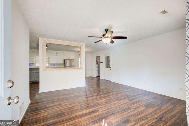 unfurnished living room featuring dark wood-style floors, visible vents, and a ceiling fan