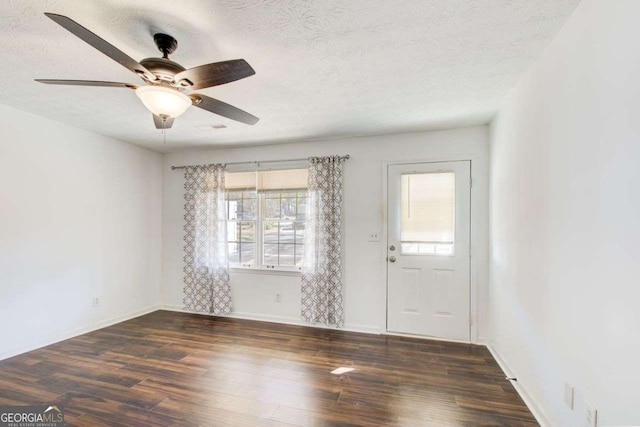 interior space with a ceiling fan, a textured ceiling, baseboards, and wood finished floors