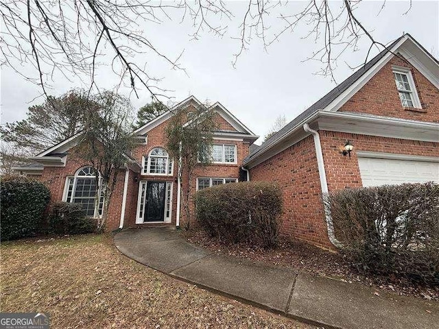 traditional-style home featuring a garage and brick siding