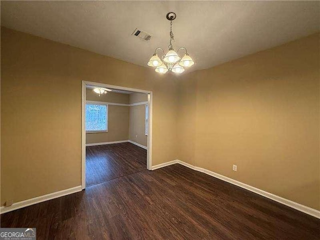 unfurnished dining area with baseboards, visible vents, a chandelier, and dark wood-type flooring