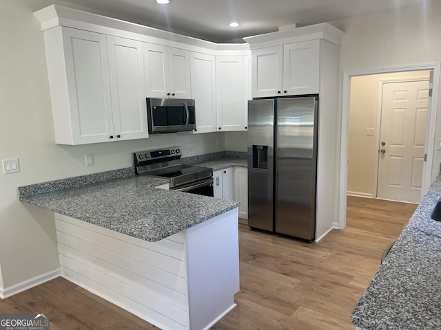 kitchen featuring stainless steel appliances, recessed lighting, light wood-style floors, white cabinetry, and a peninsula