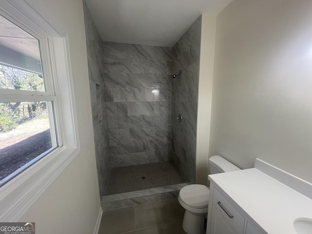 full bath with vanity, a tile shower, and toilet