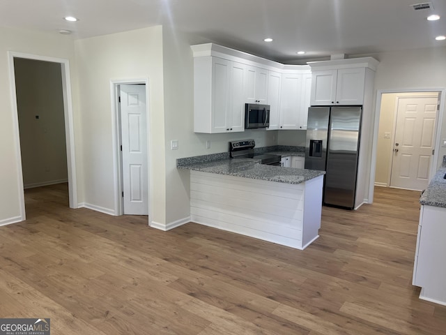 kitchen featuring recessed lighting, a peninsula, white cabinets, appliances with stainless steel finishes, and light wood-type flooring