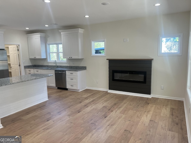 kitchen with recessed lighting, a glass covered fireplace, a sink, light wood-type flooring, and dishwasher