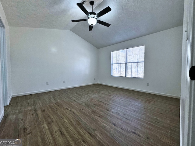 unfurnished bedroom featuring lofted ceiling, dark wood-style flooring, a textured ceiling, and baseboards