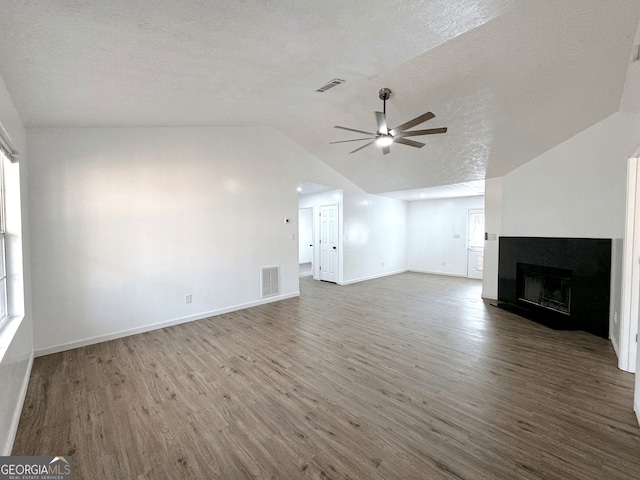 unfurnished living room with visible vents, a ceiling fan, vaulted ceiling, wood finished floors, and a tile fireplace