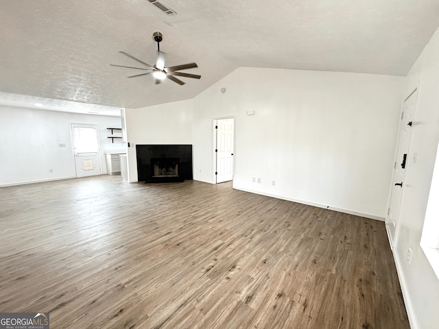 unfurnished living room featuring a fireplace, lofted ceiling, ceiling fan, a textured ceiling, and wood finished floors