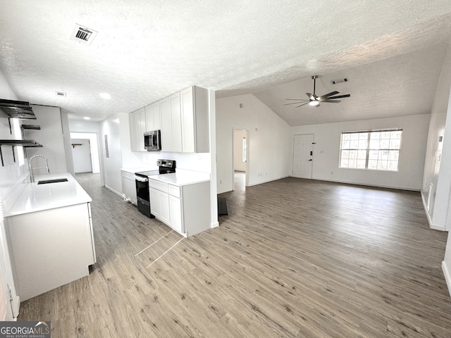 kitchen with open shelves, appliances with stainless steel finishes, white cabinets, a sink, and light wood-type flooring