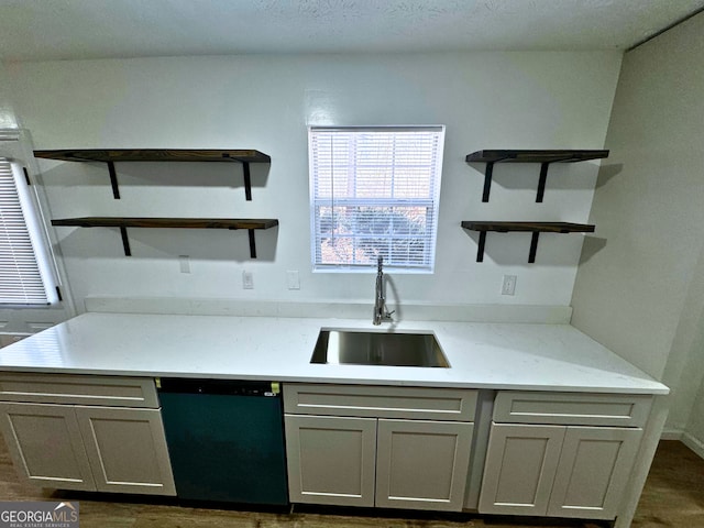 kitchen featuring dishwashing machine, a sink, gray cabinets, light stone countertops, and open shelves