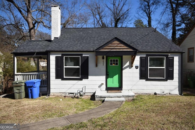 bungalow-style house featuring a shingled roof, a chimney, and a front yard