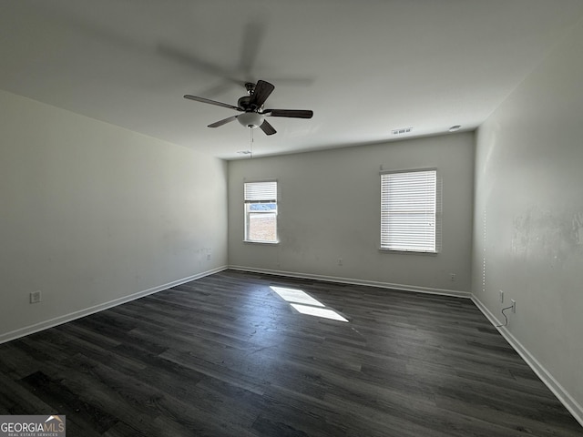 empty room featuring ceiling fan, dark wood finished floors, visible vents, and baseboards