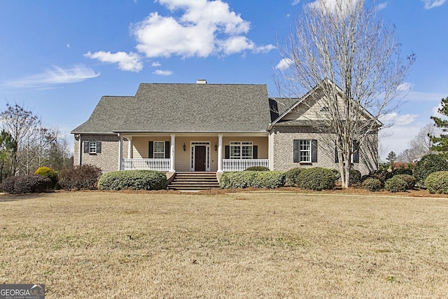 view of front facade featuring a porch, brick siding, a shingled roof, and a front lawn