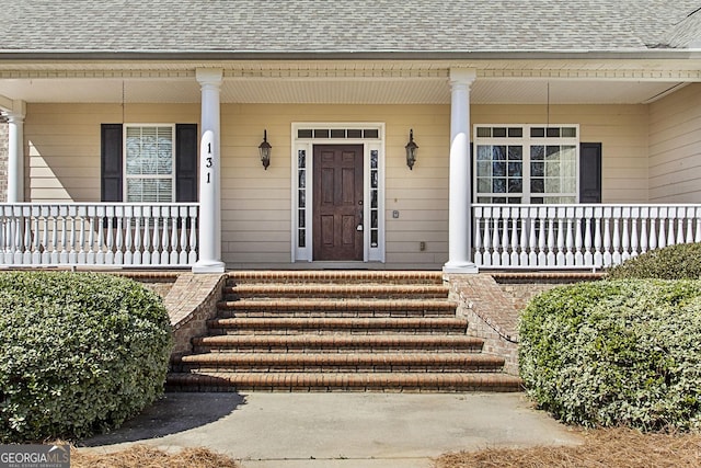 entrance to property with a shingled roof and covered porch