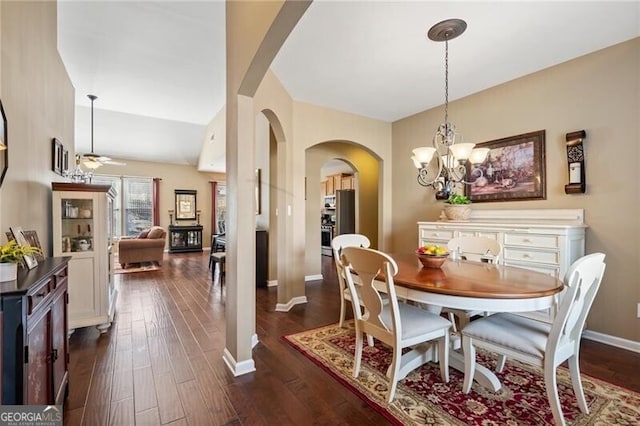 dining room featuring baseboards, arched walkways, dark wood finished floors, and ceiling fan with notable chandelier