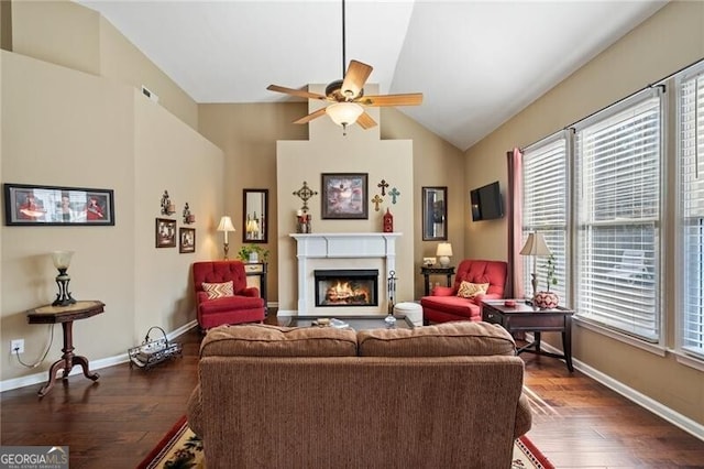 living room with a lit fireplace, baseboards, vaulted ceiling, and dark wood-type flooring