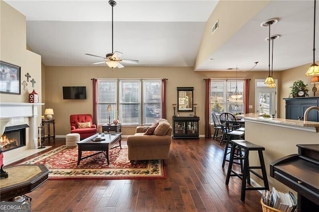 living area with dark wood-style floors, baseboards, a premium fireplace, and visible vents