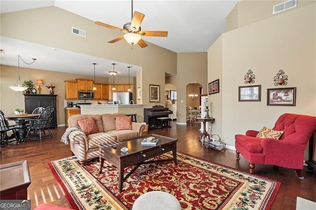 living room with visible vents, arched walkways, wood finished floors, and ceiling fan with notable chandelier