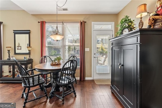 dining room featuring baseboards, visible vents, dark wood-type flooring, and a wealth of natural light