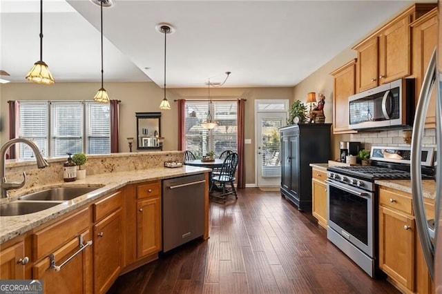 kitchen featuring tasteful backsplash, dark wood-style floors, appliances with stainless steel finishes, decorative light fixtures, and a sink