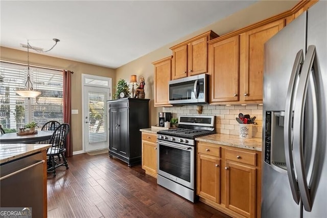 kitchen featuring appliances with stainless steel finishes, light stone countertops, tasteful backsplash, dark wood finished floors, and pendant lighting