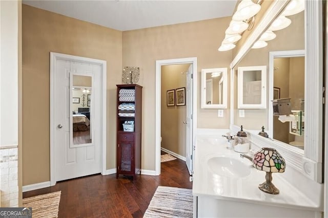 bathroom featuring double vanity, baseboards, a sink, and wood finished floors