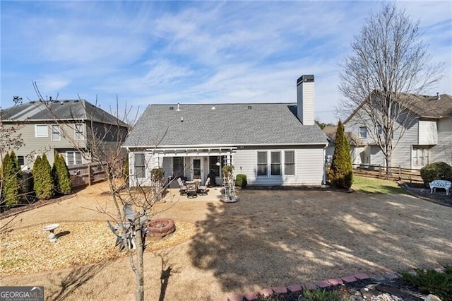 rear view of property with an outdoor fire pit, a shingled roof, a patio, a fenced backyard, and a chimney