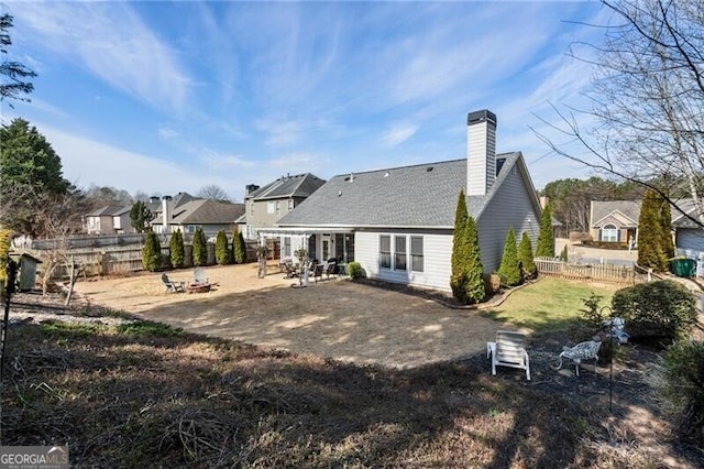 rear view of house featuring a patio, a chimney, and fence