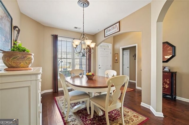 dining area featuring arched walkways, visible vents, baseboards, dark wood-style floors, and an inviting chandelier