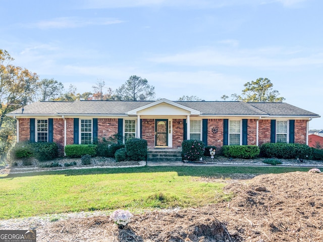 ranch-style house featuring brick siding, roof with shingles, and a front yard