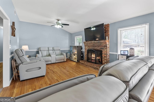 living area featuring a fireplace, vaulted ceiling, and wood finished floors