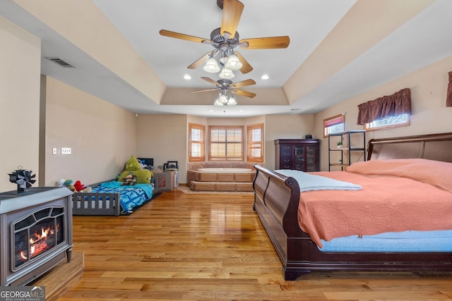 bedroom featuring light wood-style flooring, visible vents, a tray ceiling, and recessed lighting