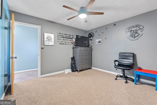 carpeted office space featuring a ceiling fan, baseboards, and a textured ceiling