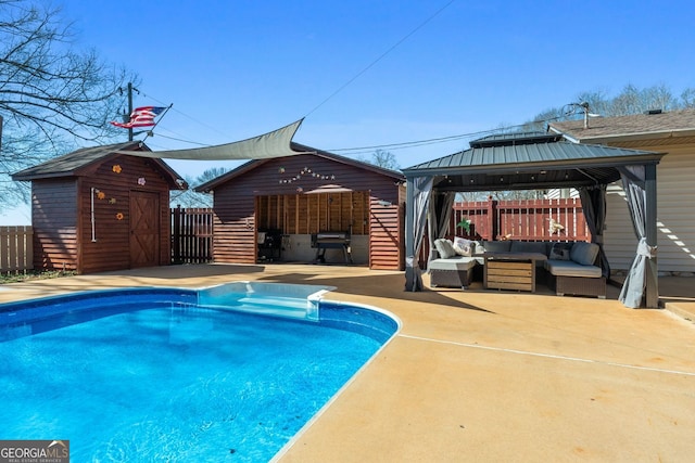 view of pool featuring an outbuilding, outdoor lounge area, a fenced in pool, and a gazebo