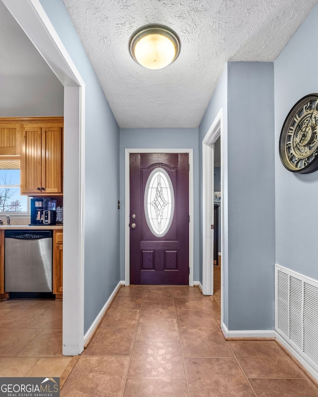 foyer entrance featuring light tile patterned floors, baseboards, visible vents, and a textured ceiling