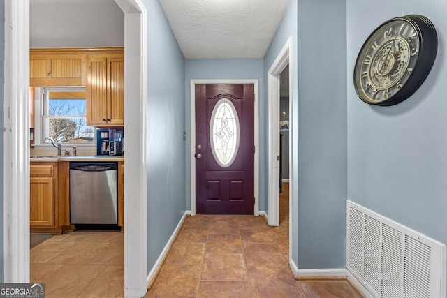 doorway featuring a textured ceiling, a wealth of natural light, a sink, and visible vents