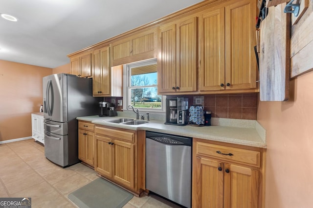 kitchen with tasteful backsplash, baseboards, stainless steel appliances, light countertops, and a sink