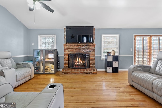 living area with lofted ceiling, a fireplace, wood finished floors, and baseboards