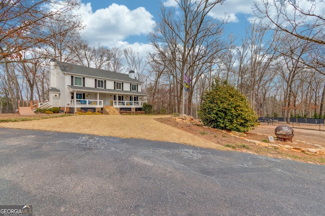 view of front of home with a porch, a chimney, and fence