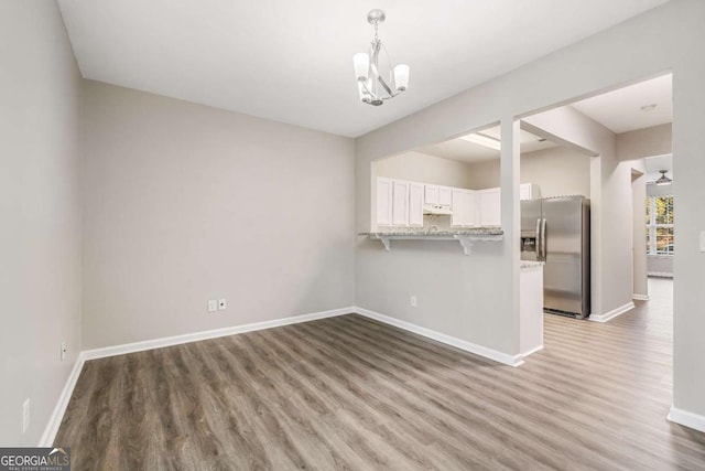 interior space featuring an inviting chandelier, baseboards, and wood finished floors