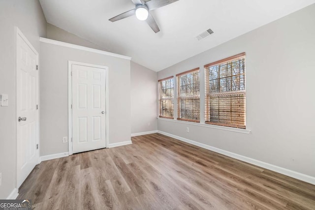 unfurnished bedroom with lofted ceiling, visible vents, ceiling fan, wood finished floors, and baseboards