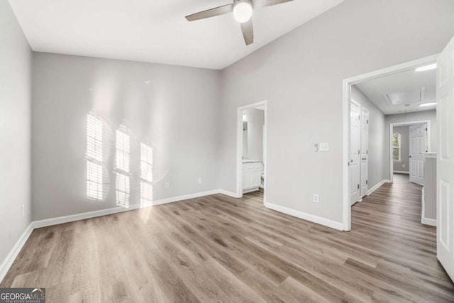 empty room featuring a ceiling fan, wood finished floors, attic access, and baseboards