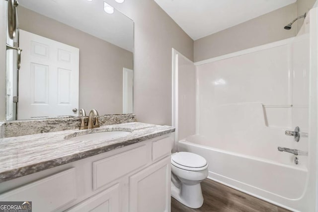 bathroom with washtub / shower combination, vanity, toilet, and wood finished floors