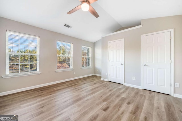 unfurnished bedroom featuring baseboards, visible vents, a ceiling fan, light wood-style flooring, and vaulted ceiling