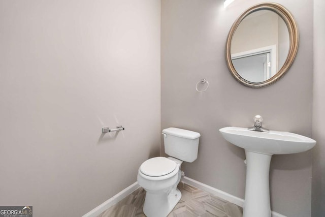 bathroom with a sink, toilet, and baseboards