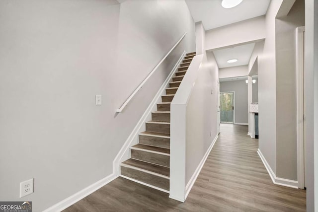 staircase with baseboards and wood finished floors