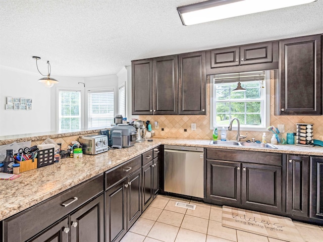 kitchen with light tile patterned floors, dark brown cabinetry, visible vents, stainless steel dishwasher, and a sink